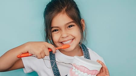 Child brushing teeth with model